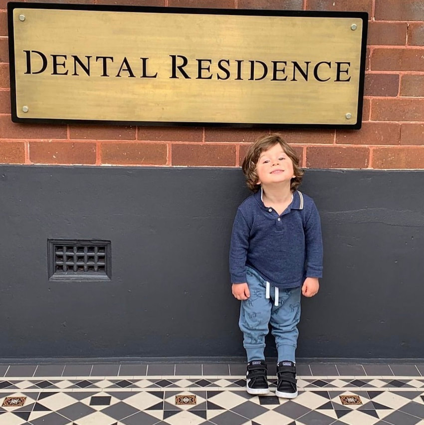 Young boy standing outside the Dental Residence - Marrickville Dentist sign.